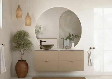 Beige vegghengt servantskap med bolleservant i glass, høyt servantbatteri og rundt speil med lys