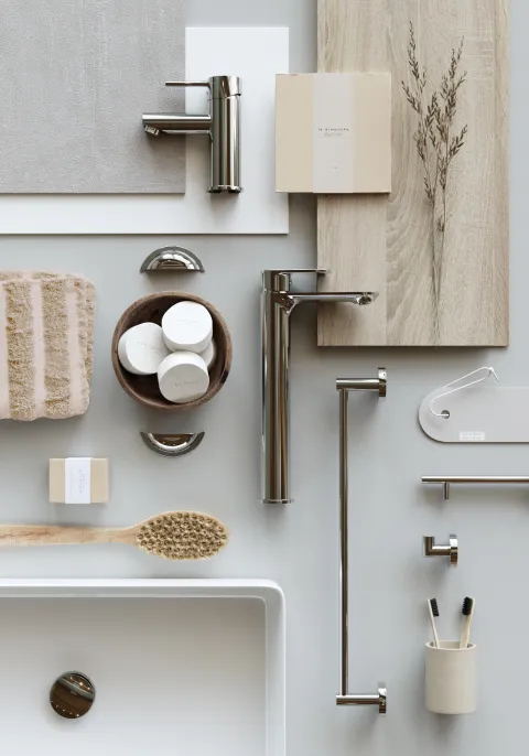 Flat lay med to blandebatterier i blankt metall, håndklestang, knagg og lyse materialprøver